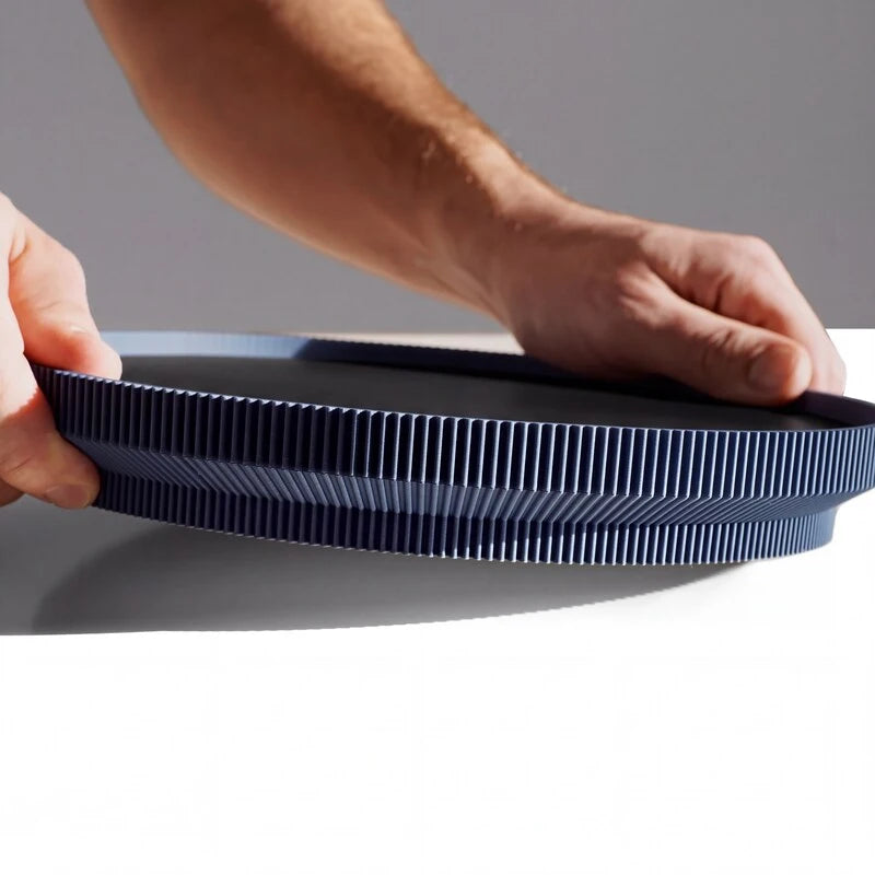 Dunkelblaues Dekotablett aus 3D Druck mit gerilltem Rand wird mit beiden Händen gehalten