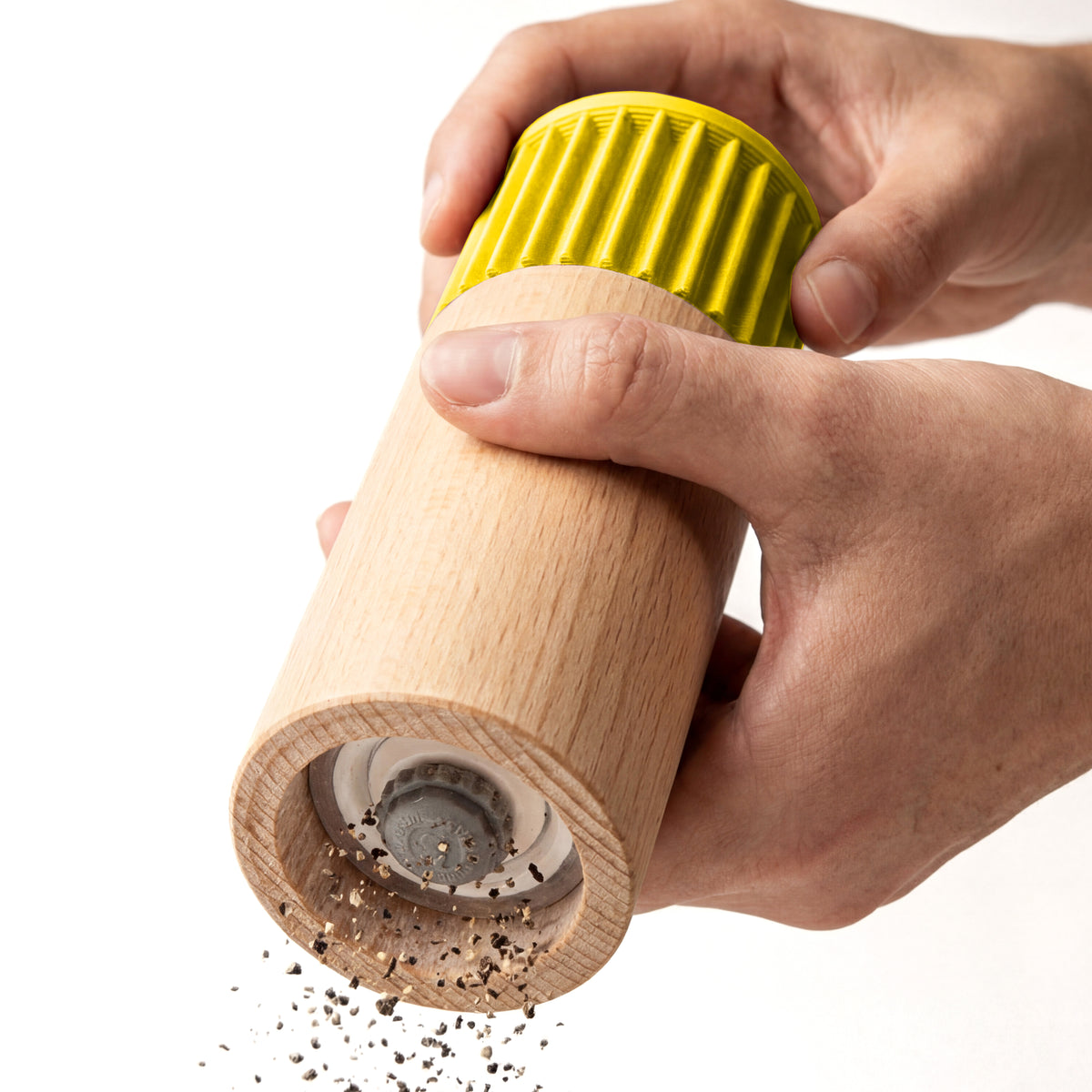Hände mahlen Pfeffer mit der Gewürzmühle Prise in Gelb aus Buchenholz vor weißem Grund #farbe_gelb