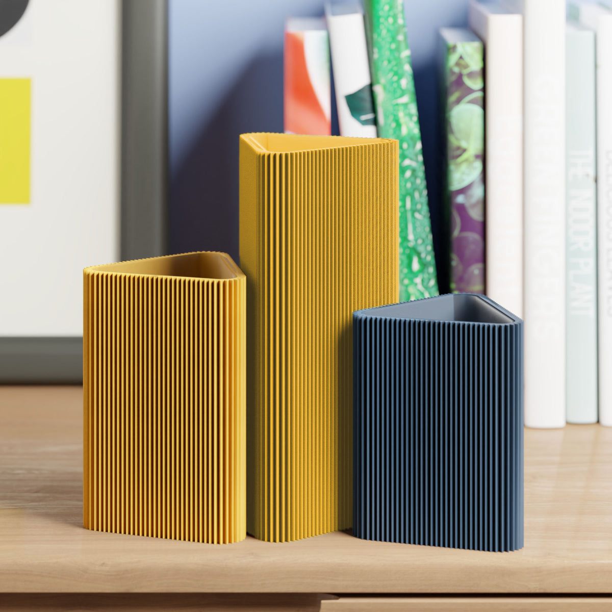 Geometrische Vase DREIECK in senfgelb mit zwei weiteren Vasen vor Büchern im Regal #farbe_senfgelb