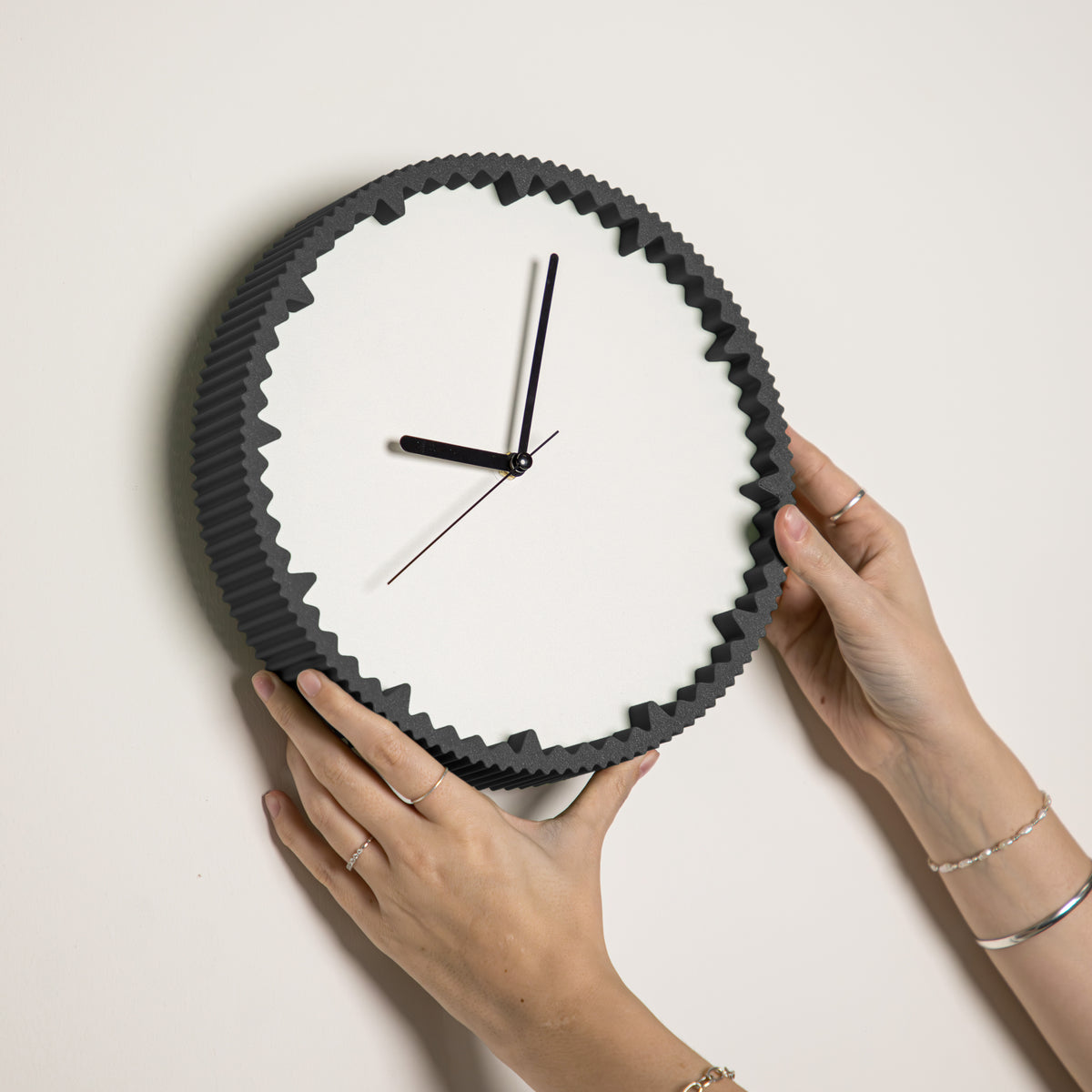 Hände hängen moderne Wanduhr schwarz mit gezacktem Rand aus dem 3D Druck an die Wand #farbe_schwarz